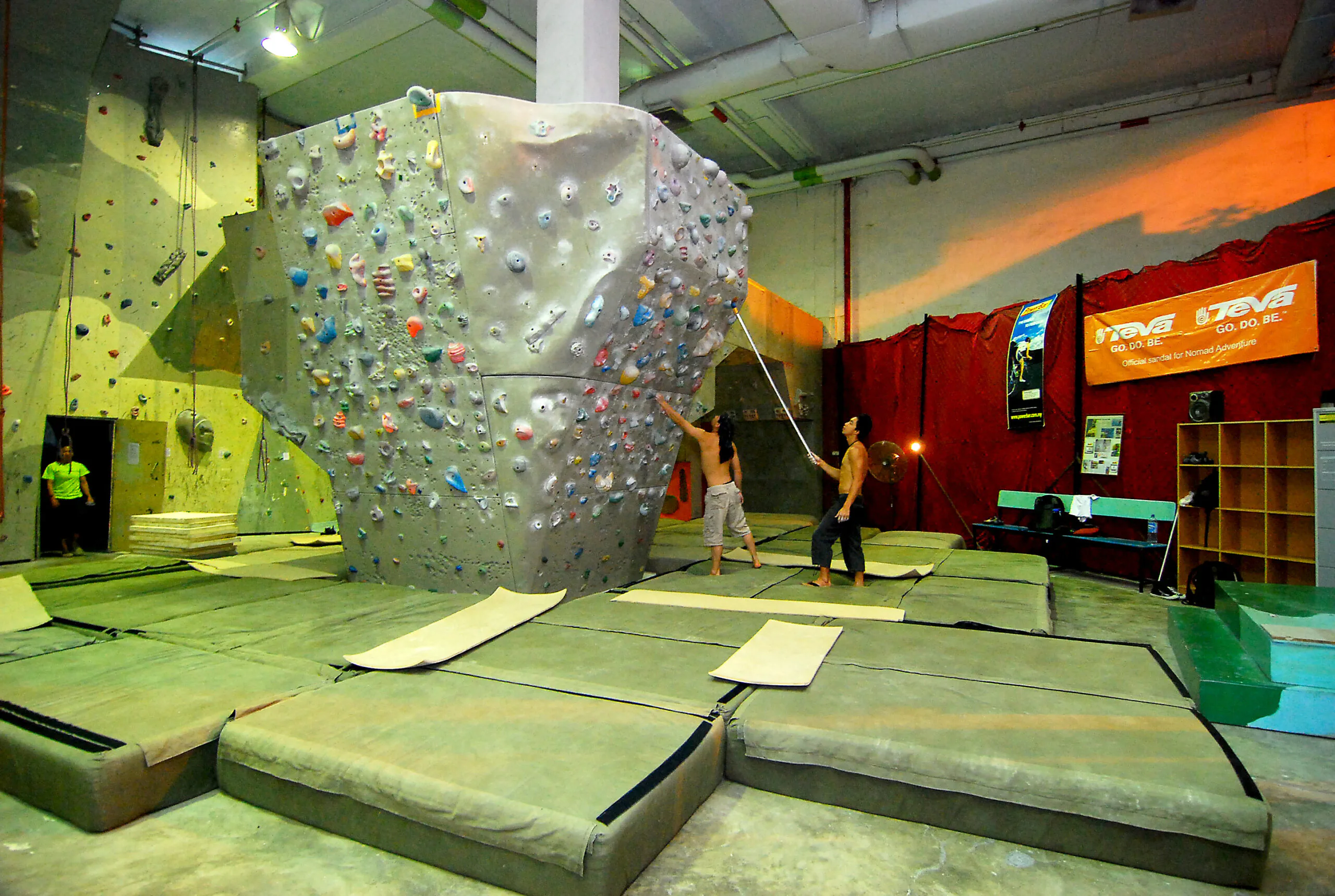 Praticante de boulder em parede de escalada com colchões de proteção