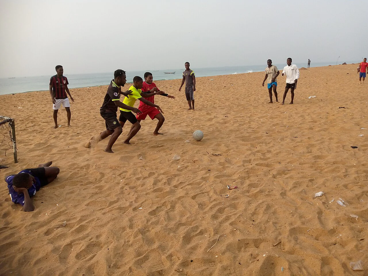 Jogadores disputam uma partida de futebol de areia na praia.