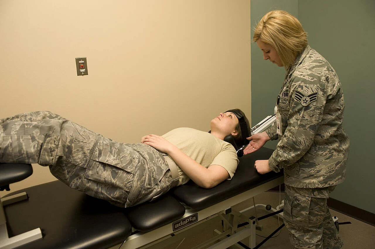 Profissional posiciona uma pessoa deitada em equipamento de tração cervical em um serviço de fisioterapia.